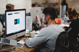 A man in an office diligently working on a computer, focused on his tasks.