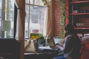 A focused woman sits at a table with a laptop, engrossed in the workshop titled 'Clickbait No More', learning to craft compelling emails. Ecommerce Email Examples