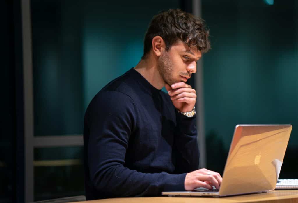 A man sitting at a desk with his laptop, engaged in email marketing.