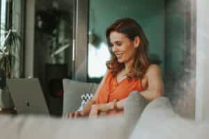 A woman engrossed in her work, sitting on a couch with a laptop, engaged in email marketing.