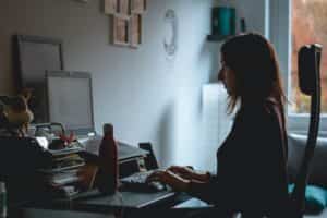 A woman sitting at a table, typing on a laptop computer